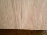 a cat that is sitting on the floor under a cabinet