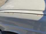 a close up of a white car with rust on it ' s hood