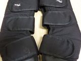 two pairs of black knee pads sitting on top of a wooden table