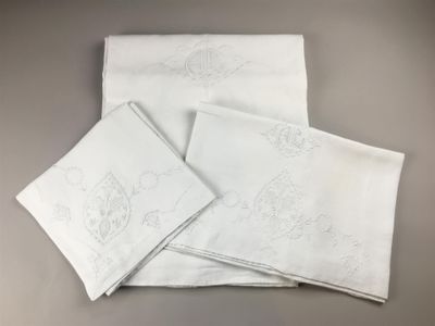 quatre serviettes blanches ornées de motifs brodés, posées sur une table