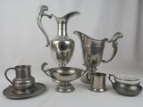 un service à thé en argent avec des tasses et des soucoupes posé sur une table