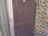 a wooden cabinet in a room with a flowered wallpaper