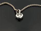 un gros plan d'un pendentif en forme de cœur en argent monté sur une chaîne