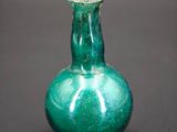 a green glass vase sitting on a black surface