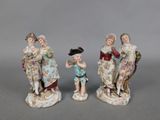 three porcelain figurines of a boy and a girl with a bird