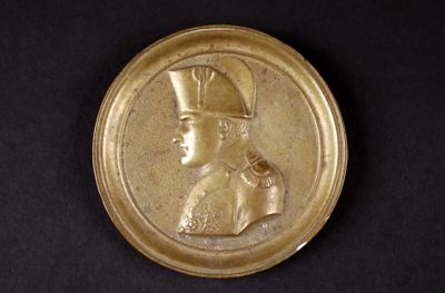 une image représentant une assiette en or sur laquelle figure le portrait d'un homme coiffé d'un chapeau