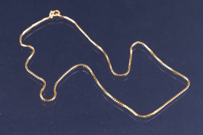 un collier en or sur un fond bleu, avec une chaîne en or