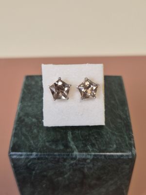 a pair of earrings sitting on top of a marble block