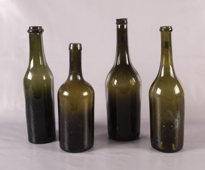 trois bouteilles de vin vides posées les unes à côté des autres sur une surface blanche