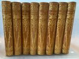 six old books are lined up in a row on a table