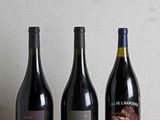 trois bouteilles de vin sont alignées sur une table en bois