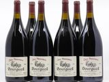 quatre bouteilles de vin rouge sont alignées sur une surface blanche
