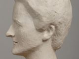 a white sculpture of a woman ' s head on a table