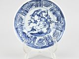 blue and white plate with a dragon on it on a stand