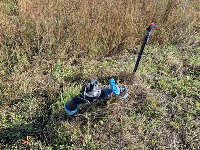 un tuyau bleu et un autre tuyau bleu posés par terre dans l'herbe
