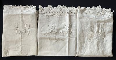 three white linen napkins with embroidered monograms on them