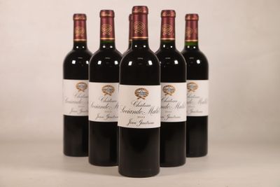 quatre bouteilles de vin rouge sont alignées sur une table