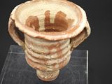 une image représentant un vase en argile posé sur un socle transparent