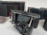 four old cameras sitting on a white surface