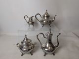 three silver teapots and a tea pot on a table