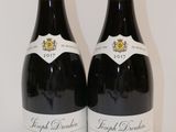 deux bouteilles de vin rouge posées sur une table blanche