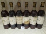 six bottles of wine are lined up in a row on a table