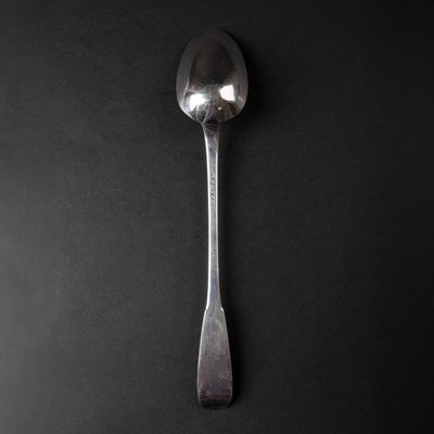 a silver spoon with a spoon handle on a black surface