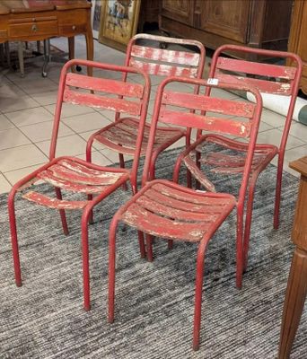 quatre chaises rouges en métal posées sur un tapis dans un salon