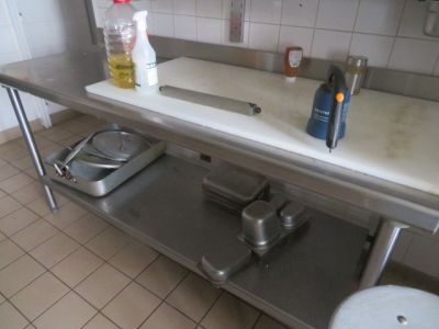 une cuisine équipée d'un évier et d'un plan de travail sur lequel se trouve une planche à découper