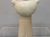 un vase blanc exposé sur une étagère transparente
