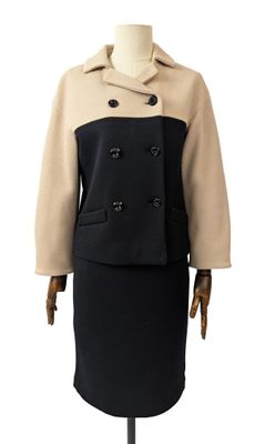 Le mannequin porte une robe et un manteau noirs et beiges.