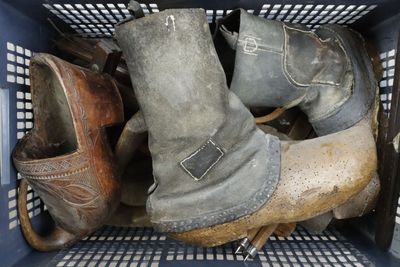 many pairs of old boots in a blue basket
