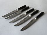 six knives are lined up on a white surface with a black handle