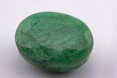 un gros plan d'une pierre verte sur une surface blanche
