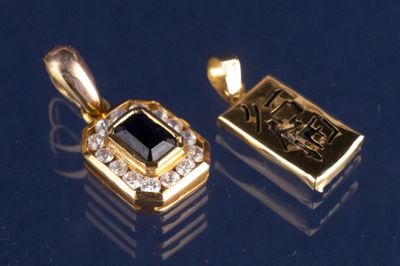 deux pendentifs en or sertis d'une pierre noire et de diamants sur un fond bleu