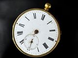 a gold pocket watch with roman numerals on the face