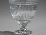 a glass cup sitting on a table with a shadow on the table