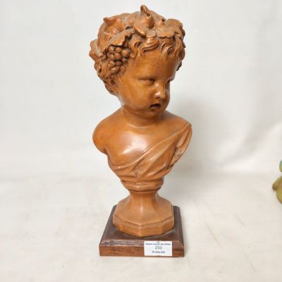 deux statues représentant un garçon aux cheveux bouclés, posées sur un socle en bois