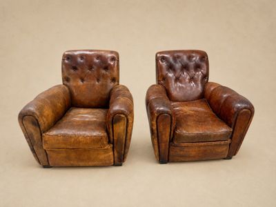 deux fauteuils en cuir marron placés l'un à côté de l'autre sur une surface beige