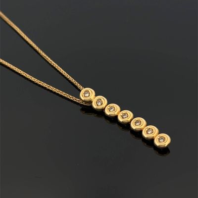 a gold necklace with five diamonds on a black surface