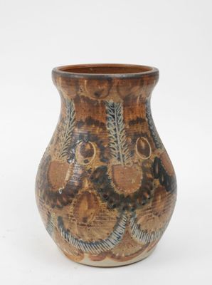 un vase brun orné d'un motif sur une surface blanche