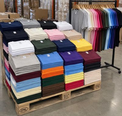 de nombreux t-shirts de différentes couleurs sur une palette dans un magasin