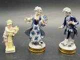three porcelain figurines of a man and a woman in blue and white