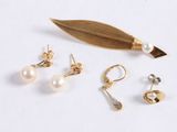 three pairs of earrings and a leaf on a white surface