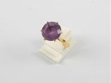 gros plan d'un anneau de pierre violette sur une surface blanche