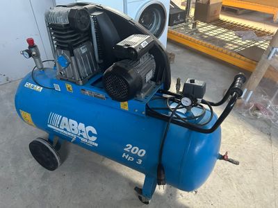 un compresseur d'air bleu posé sur un chariot dans un garage