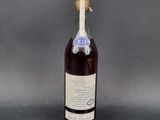 une vieille bouteille de vin posée sur une table, sur fond gris