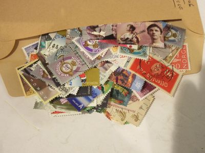 une enveloppe marron remplie de timbres, posée sur une table blanche