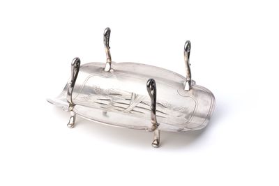 une assiette en argent munie d'une poignée, posée sur une surface blanche