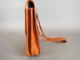 an orange leather purse with a strap on a white background